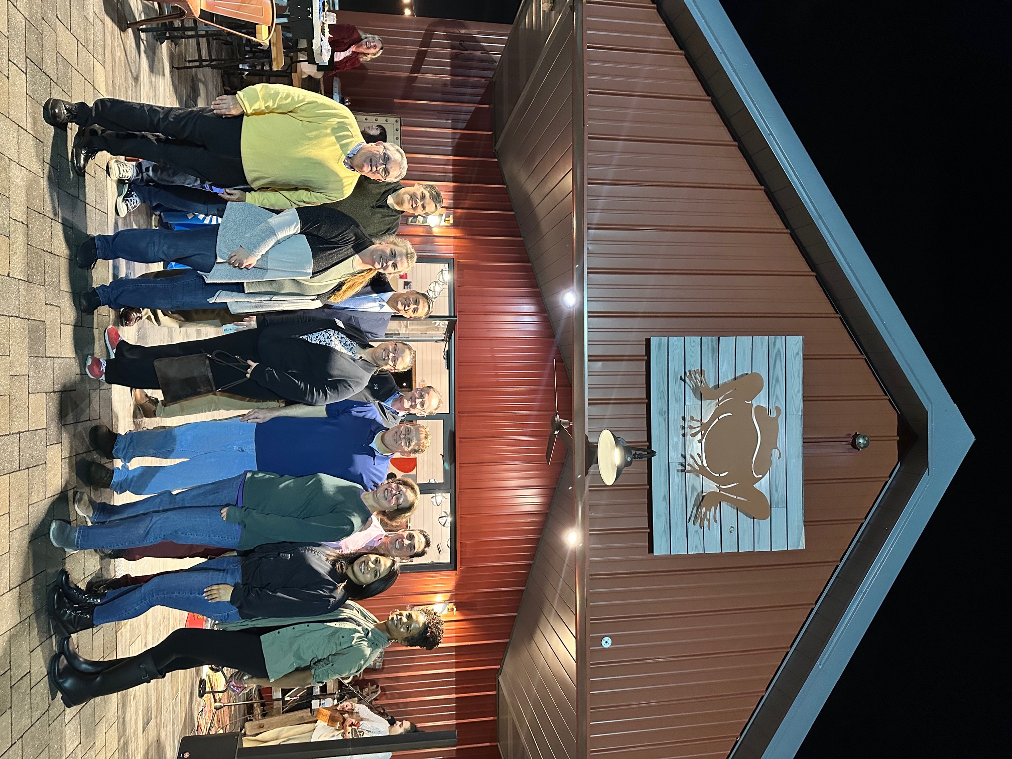 A group of people posing together in front of Great Frogs Winery.