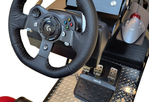 A close-up of the wheel, mouse, and pedals of a driving simulator.