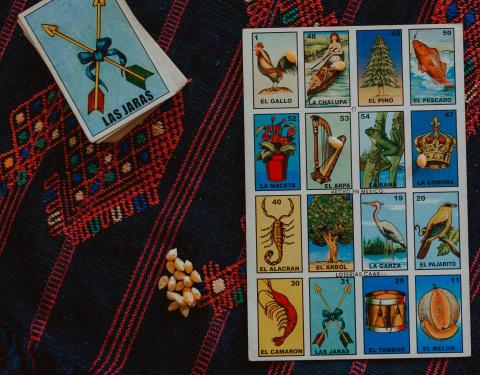 Image depicts a loteria gameboard, dried corn, and playing card.