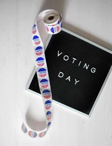 black and white sign that says voting day next to voting stickers