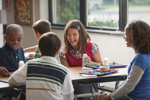 A group of children eating lunch together at a cafeteria table.