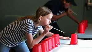 Young child playing a game with red cups and straws