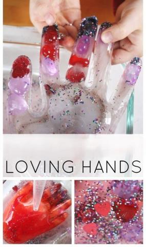 Picture of child hands melting a frozen hand that has beads shaped like hearts.