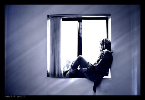 black and white image of person sitting in a window looking out