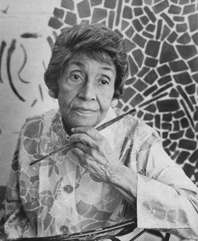 A portrait of Alma Thomas in front of one of her works.