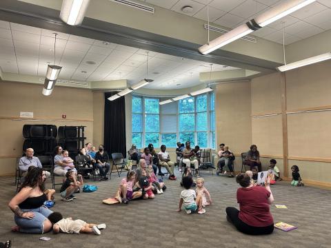 a group of adults and children sitting on the floor for storytime