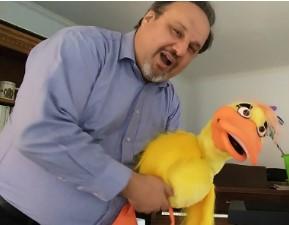 Middle aged man smiling and holding large yellow duck puppet