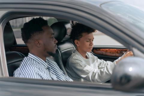 An image of a teen and adult driving in a car together. 