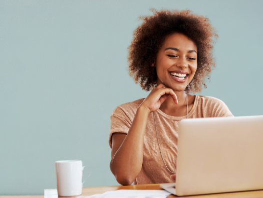 Woman on a blue background smiling at a laptop computer