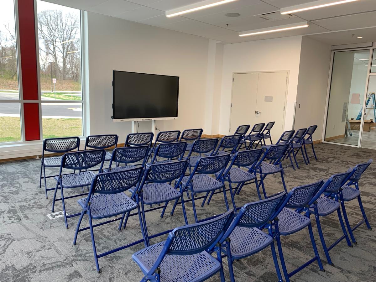 Meeting space with chairs set up in rows and a screen at the front of the room.