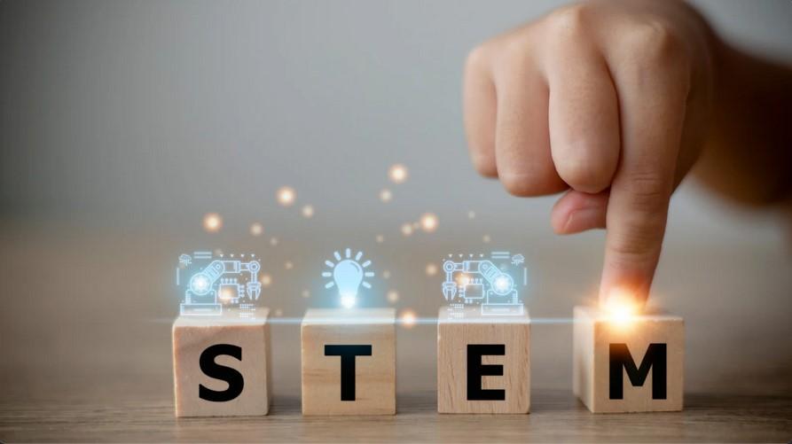 a child's hand taping four wooden blocks that spell out the word STEM